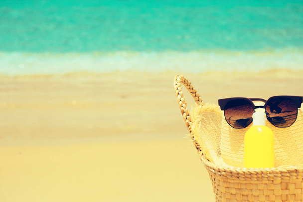 Cappello di paglia, borsa di paglia, occhiali da sole e una bottiglia di crema solare lotio
 - Foto, immagini