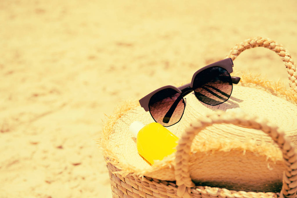 Sombrero de paja, una botella de loción protector solar, gafas de sol y ba de paja
 - Foto, Imagen