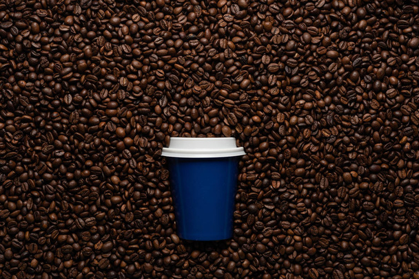 Blue disposable cup to go, on the background of coffee beans with empty space for text. - Valokuva, kuva