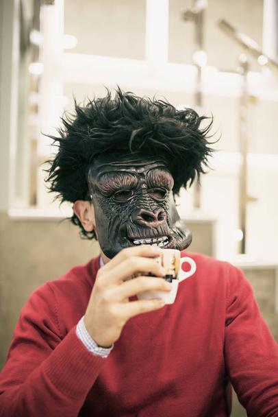 Homem com máscara de gorila bebendo café
 - Foto, Imagem