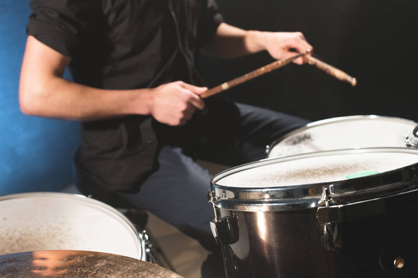 Close-up of a male drummers hand holding drum sticks while sitting behind a drum set - Foto, Bild