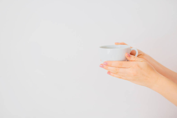 Female hands holding mug on a white background. - Photo, Image