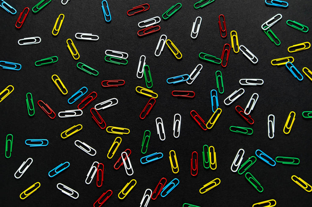 colored paper clips on a black background - Foto, imagen