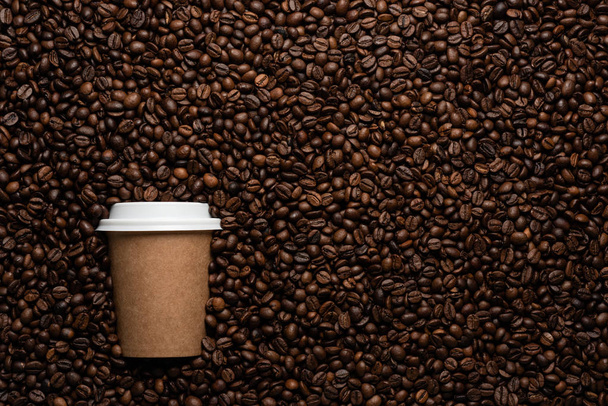 Kraft disposable cup to go, on the background of coffee beans with empty space for text. - Φωτογραφία, εικόνα