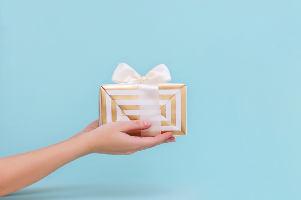 Womans hands holding gift or present box on blue pastel background. - Photo, Image