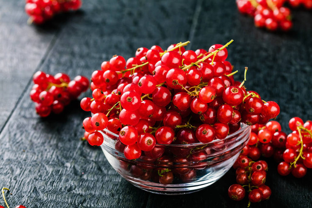 close-up view of glass bowl with fresh red currants on wooden table   - Foto, Imagen