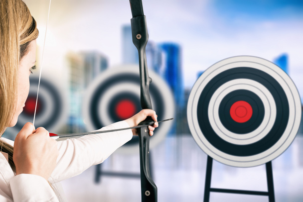 Mujer de negocios con arco y flecha apuntando al centro del objetivo
 - Foto, Imagen