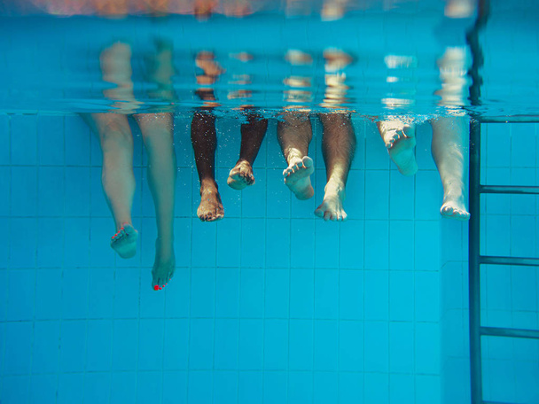 quatro pessoas pernas debaixo d 'água na piscina. Festa. Verão. Férias, diversidade, amizade e conceito de esporte
. - Foto, Imagem