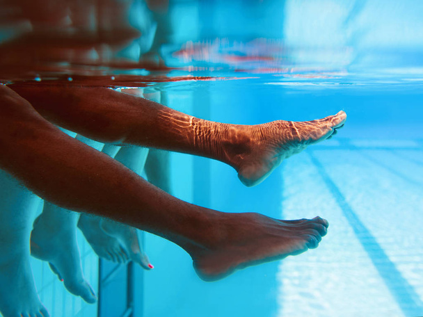 Az afro-amerikai férfi lábak, kaukázusi barátokkal a víz alatti medencében. Nyári. Vakáció, nemzetközi és sportkoncepció. - Fotó, kép