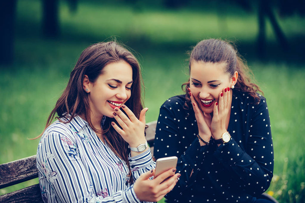 Vrouwelijke vrienden kijken naar Video's op een smartphone en verraste Loo - Foto, afbeelding