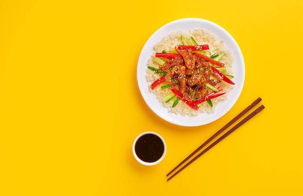 Stir-fry with chicken meat, vegetables and rice on colorful background. Copy space, top view - 写真・画像