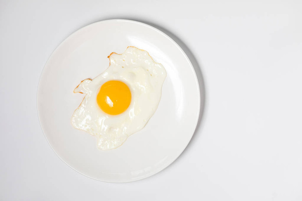 Fried egg on a white plate. Isolated on white background - Foto, afbeelding