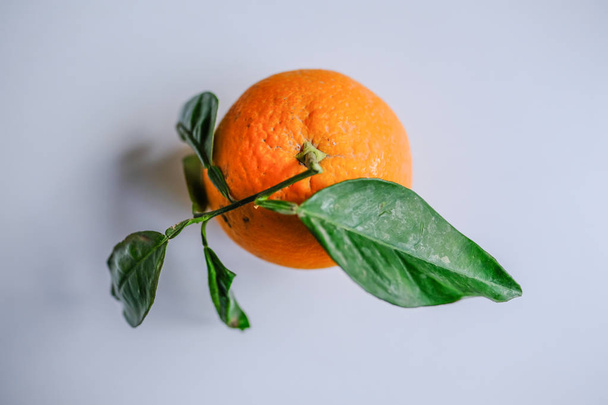 Вид сверху одного спелого апельсина с зелеными листьями
. - Фото, изображение