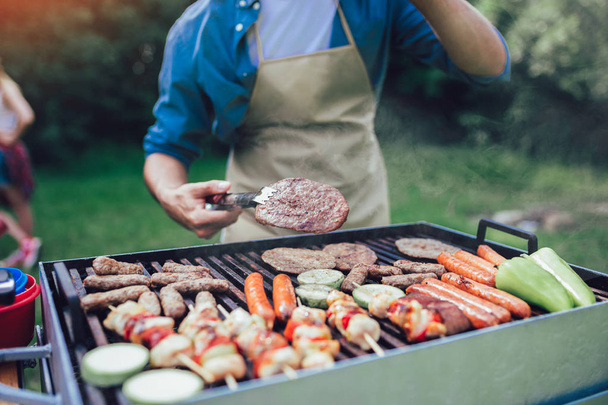 Handsome male preparing barbecue outdoors for friends - Photo, Image