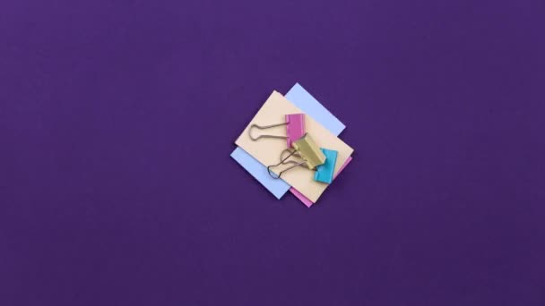 Stop motion school stationery animated. Back to school concept. Calculator, pencils, paper clips, stapler and orange paper in turn appear on a purple background with empty space for text. - Felvétel, videó