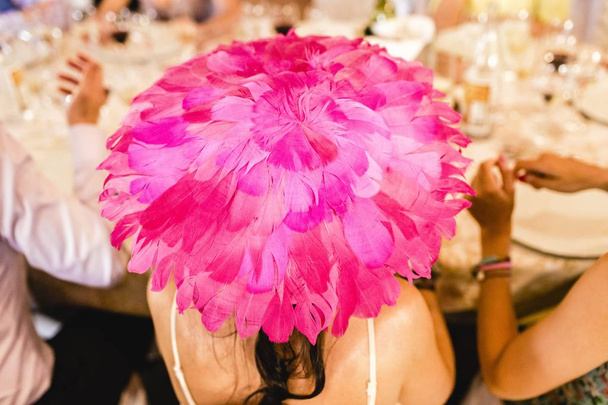 Donna invitata a un matrimonio indossa un grande cappello di piuma viola in spr
 - Foto, immagini