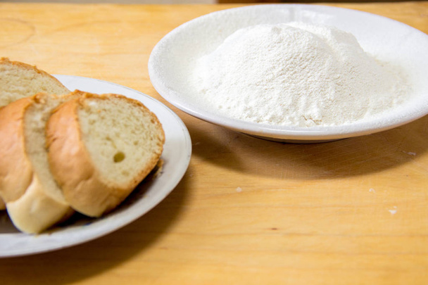 Slices of bread and wheat flour in a white plate on the table - Photo, Image
