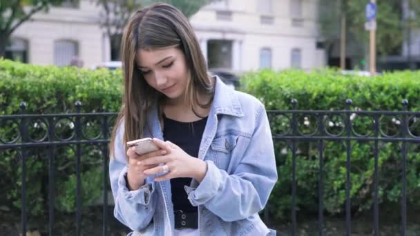 Tiener meisje typt een bericht op de smartphone in vierkant - Video