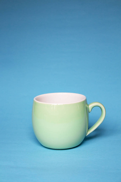 Cup green on a blue background. Tableware or cup for cafes, rest - Photo, image