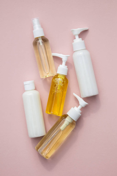 A collection of beauty cosmetic producs in clear bottles on a pink background - Fotó, kép