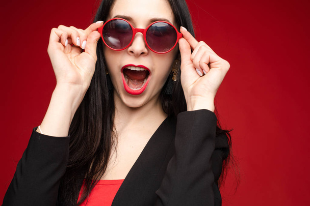 Mujer divertida feliz con gafas de sol de color rojo brillante
. - Foto, imagen