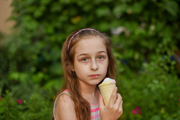 Niña comer helado al aire libre En un vestido brillante a rayas de colores. Soleado verano, clima caluroso
. - Foto, Imagen