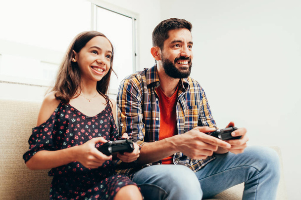 Sorridente padre e figlia giocare al videogioco a casa
 - Foto, immagini