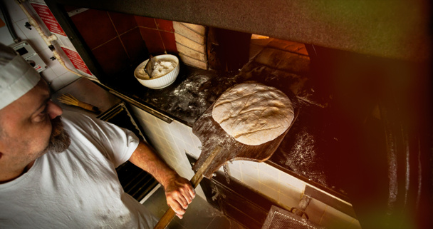 Produkcja chleba upieczony z piec opalany drewnem, w piekarni. - Zdjęcie, obraz