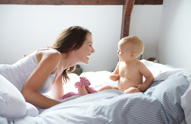 Mother and baby playing on bed - Photo, Image