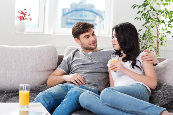 Couple sitting on couch and drinking orange juice - Fotó, kép