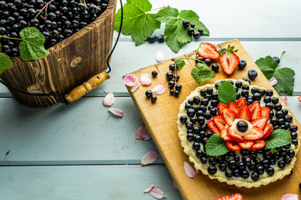 Cake with berries Pie with strawberries and black currants on blue rustic table. - Foto, Imagen