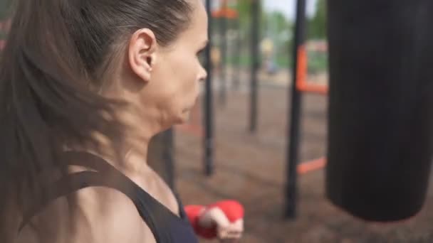 Woman kikboxer beats with  leg boxing bag .City kickboxing training outdoor.  - Záběry, video