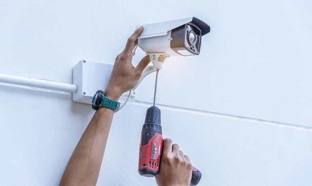 Technician installing wireless CCTV security camera by hand screwdriver  with waterproof white plastic box for protection CCTV from water or rain. - Foto, Bild
