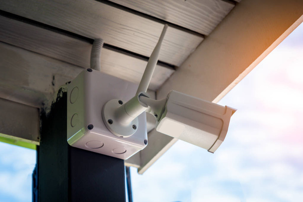 Technicus installeren draadloze CCTV-beveiligingscamera met de hand schroevendraaier met waterdichte witte plastic doos voor bescherming CCTV van water of regen. - Foto, afbeelding