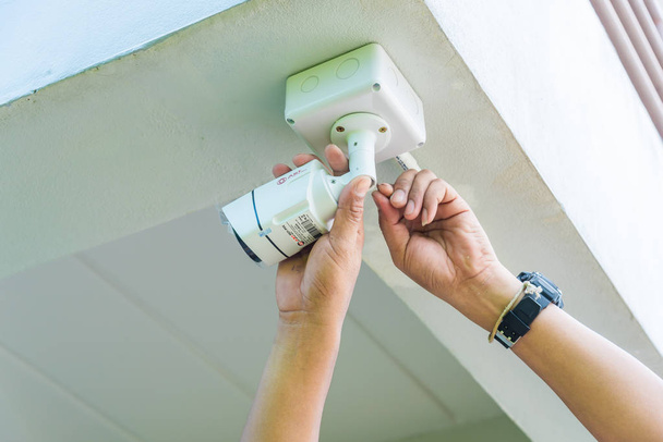 Technician installing wireless CCTV security camera by hand screwdriver  with waterproof white plastic box for protection CCTV from water or rain. - Foto, immagini