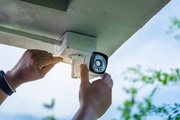 Tecnico che installa telecamera di sicurezza CCTV wireless a mano cacciavite con scatola di plastica bianca impermeabile per la protezione CCTV da acqua o pioggia
. - Foto, immagini