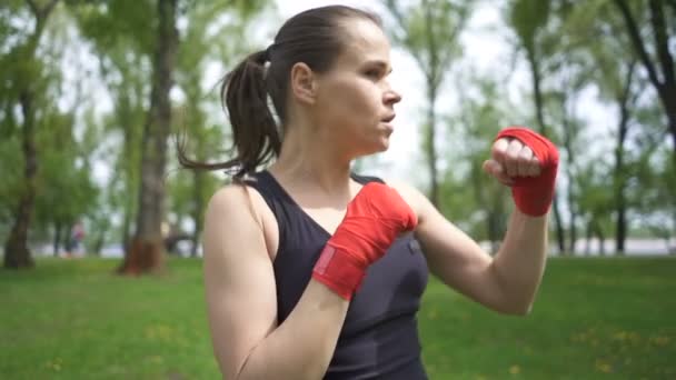 Vrouwelijke Boxer training met Pons zakken op Street City Park, steady shot, laterale weergave - Video