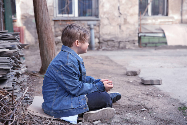 Homeless little boy sitting outdoors - Photo, Image