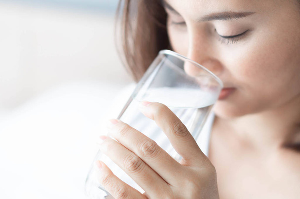 Cerca de la mujer que bebe agua pura de vidrio con luz en la mañana, enfoque selectivo - Foto, imagen