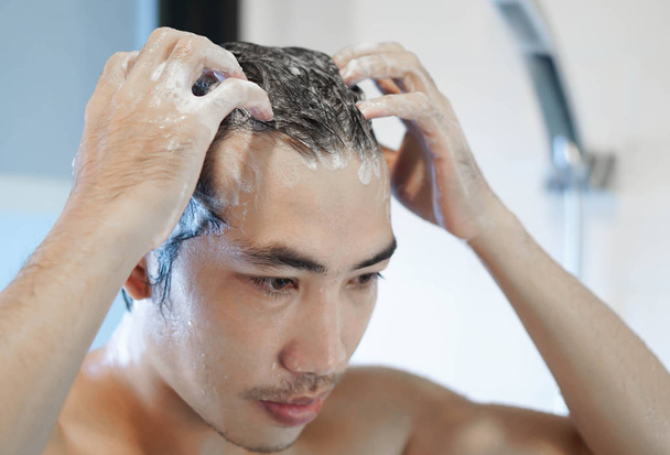 Крупный план молодой человек моет волосы с шампунем в ванной комнате, винтажный тон, избирательный фокус
 - Фото, изображение