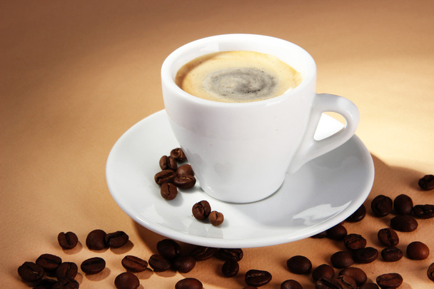 Tasse Kaffee mit Kaffeebohnen auf beigem Hintergrund - Foto, Bild