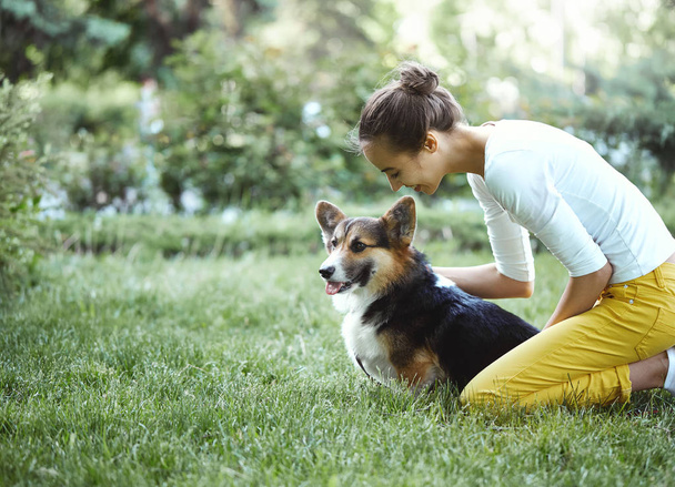 Welsh Corgi Pembroke dog and smiling happy woman together in a park outdoors. - Photo, image