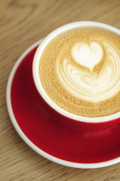 Ahşap alan arka planda latte sanatı ile kapuçino güzel bir fincan. Minimal kompozisyon, hipster titreşimleri.  - Fotoğraf, Görsel