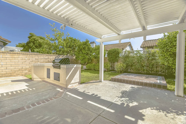 Terrasse en béton d'une maison avec barbecue et pergola en bois blanc
 - Photo, image