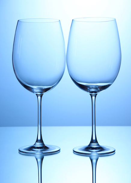 Empty wine glasses arranged on blue background - Foto, afbeelding