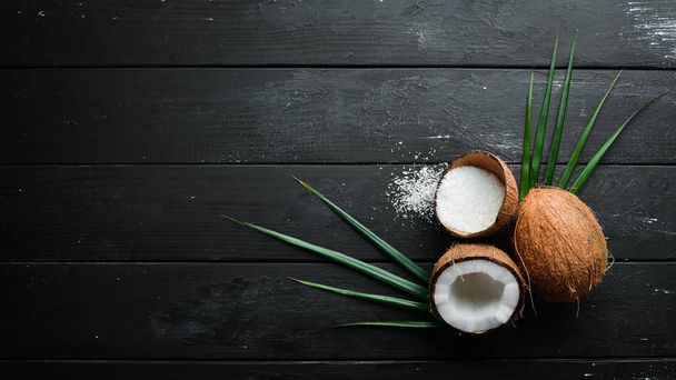 Fresh coconut on a black background. Tropical Fruits. Nut. Top view. Free space for your text. - Foto, imagen