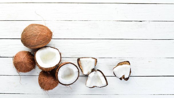 Fresh coconut on a white wooden background. Tropical Fruits. Nut. Top view. Free space for your text. - Φωτογραφία, εικόνα