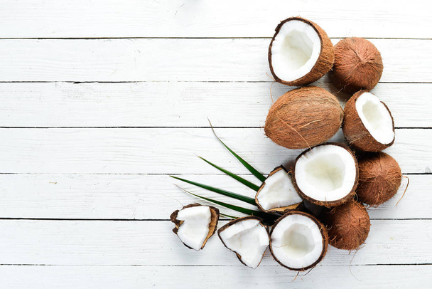 Fresh coconut on a white wooden background. Tropical Fruits. Nut. Top view. Free space for your text. - Valokuva, kuva