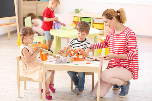 Nursery teacher with cute little children in kindergarten - Foto, immagini
