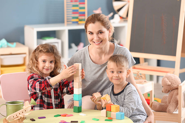 Nursery teacher with cute little children in kindergarten - Фото, изображение